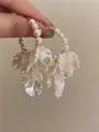 Close-up detail of elegant pearl flower earrings with intricate white petal designs. - Style 11
