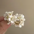 Close-up of elegant white pearl flower earrings with gold accents and sparkling stones - Style 9