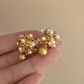 Elegant matte gold flower stud earrings with delicate pearls and unique sphere backings - Style 12