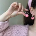 Orecchini a cerchio con perla rosa e ago d'argento mostrati da modella asiatica - Cerchio Semplice a Sfera Rosa