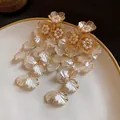 Gros plan de boucles d'oreilles fleuries élégantes avec perles et pétales nacrés blancs - Flower Tassel Style (HE29413) / Or-Blanc
