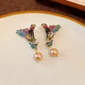 Detailed view of vintage style bird earrings with colorful rhinestones and faux pearls. - Silver Earring Post Earrings / Gold-Multicolor