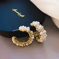 Primer plano de pendientes de aro en C dorados con perlas blancas y cristales brillantes - Pendientes de Perlas Artificiales Multihileras en C / Dorado