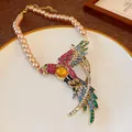 Detailed macro shot of vintage palace style necklace with a colorful rhinestone bird pendant - Necklace / Gold-Multicolor