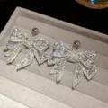 Macro view of sparkly bow-shaped earrings encrusted with clear cubic zirconia stones. - Silver White (19#)