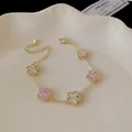 Macro detail of elegant gold plated five-flower bracelet with pink and white shell petals - Five-Flower Style / Gold-Pink