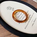 Close-up detail view of a translucent amber resin bangle on a vintage display board. - Amber Irregular Thin Style 6