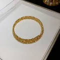 Dettaglio del bracciale rigido dorato a più strati con design a grana metallica irregolare. - Oro