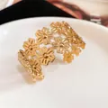 Close-up of elegant gold floral hollow-out cuff bracelet on white ceramic plate - Hollow Flower Style (HB5173-1) / Gold