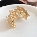 Close-up of gold-tone star cuff bracelet featuring textured starfish motifs and spirals. - Wrinkled Star Style (HB5173-1) / Gold