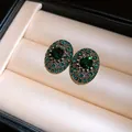 Detailed macro view of vintage oval earrings featuring emerald green crystals in a display box - Green