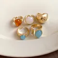 Close-up of gold-plated geometric open rings with colorful stones on a ceramic plate. - Gold (5-Piece Set)