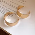 Close-up detail of polished gold-finished vintage C-shaped hoop earrings on a book - C-Shape Hoop / Gold