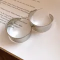 Detailed macro shot of vintage minimalist silver C-shaped hoop earrings on a book page - C-Shape Hoop / Silver