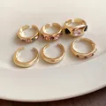 Close-up detail of six gold-plated open rings featuring pink and purple crystal accents - Gold (6-Piece Set)