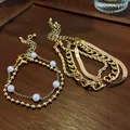 Gros plan de bracelets dorés vintage avec perles et chaînes en os de serpent. - Or