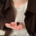 Detail showing a model wearing an adjustable long necklace with brown flocked grape pendant - Gold Brown
