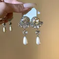 Exquisite close-up of sparkling flower rhinestone earrings with elegant white pearl teardrops - Silver