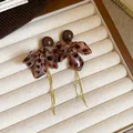 Gros plan de boucles d'oreilles fleur léopard avec longs pompons dorés dans un plateau - 5# Café - Gland Léopard