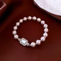 Elegant pearl bracelet featuring a sparkling crystal clasp on dark silk background. - Silver Pink Style