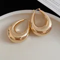 Gros plan de boucles d'oreilles créoles dorées en forme de goutte d'eau surdimensionnées - Or