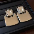 Detailed macro view of exaggerated square metal stud earrings with clear crystals - Silver