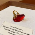 Close-up of a vintage-style red resin oval open ring with a gold adjustable band. - Oval Open Ring / Red