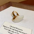 Detail macro view of an elegant gold ring with a smooth cream oval resin stone - Oval Open Ring / White