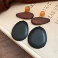 Close-up detail of minimalist ethnic statement earrings with wood and black stone texture - Coffee-Black