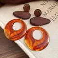 Close-up of vintage wood and amber-colored resin drop earrings displayed on a book - Amber