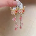 Detail shot of butterfly crystal tassel earrings featuring pink flowers and delicate pearls - Silver Earring Post - Gold - Pink