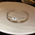 Primer plano de una elegante pulsera de doble capa plateada con mariposas de circón - Estilo Mariposa Doble Hueca / Plateado