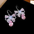 Close-up of elegant bow earrings with pink teardrop crystals and sparkling zircons. - Bow Tassel Earring Hooks / Pink