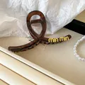 Elegant brown transparent hair claw clip featuring gold lettering on textured surface - Amber Letter Style / Coffee