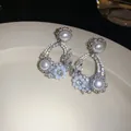 Primo piano di eleganti orecchini a fiore in argento con perle lucenti e cristalli scintillanti - Stile Cerchio Floreale con Perle / Un paio / Argento