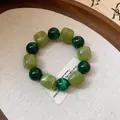 Close-up view of a green acrylic beaded bracelet with round and cube geometric bead shapes - Green