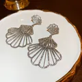 Close-up of sparkling tiered shell-shaped earrings with rhinestones on a white plate - 50# 925 Sterling Silver Earring Post - Silver (Fan)