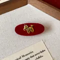 Close-up detail of a red velvet oval hair clip featuring a golden poodle with star patterns - Gold Puppy Decor Alligator Clip