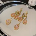 Close-up of French vintage star earrings with pink crystal teardrops on a mirror surface. - Star Water Drop Tassel Style / Gold