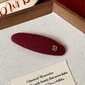 Close-up detail of burgundy velvet hair clip featuring a gold metal letter B ornament - Metal Letter B Oval BB Clip