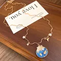 Detailed view of bohemian gold chain necklace featuring blue shell and pearl charms - Enamel Shell Style