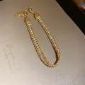 Detailed view of gold-tone bracelet featuring twisted chain and sparkling rhinestones. - Gold