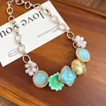 Detail of a bohemian necklace with pearl flowers and teal charms on a wooden tray - Blue-Green Flower Style