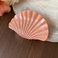 Nahaufnahme einer perlmuttfarbenen rosa Muschel-Haarklammer mit schimmerndem Iris-Finish - L / Orange
