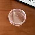 Detailed top-down view of a clear round plastic jewelry storage box on a wooden surface. - 5# Storage Box - Round (Large)