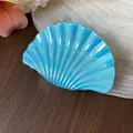 Nahaufnahme einer schillernden blauen Haarspange in Muschelform auf weichem Stoff - L / Dunkelblau