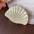 Detailansicht einer irisierenden Haarspange in Muschelform auf elegantem Seidenstoff - L / Gelb