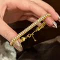 Detaillierte Makroansicht eines eleganten französischen Retro-Goldarmbands mit Kristallen. - Gold