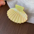 Macro view of a light yellow iridescent seashell-shaped hair claw clip for women. - S / Yellow