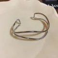 Dettaglio di un bracciale rigido aperto in metallo argentato multistrato dallo stile minimalista - Onda Multistrato / Argento